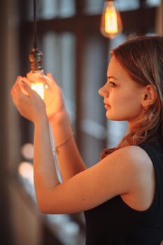 Girl holding a large incandescent lamp in the studio in her hands