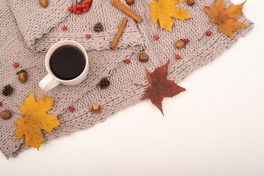 Autumn flat lay. Maple leaves, acorns and a cup of black coffee on a gray blanket. Copy space