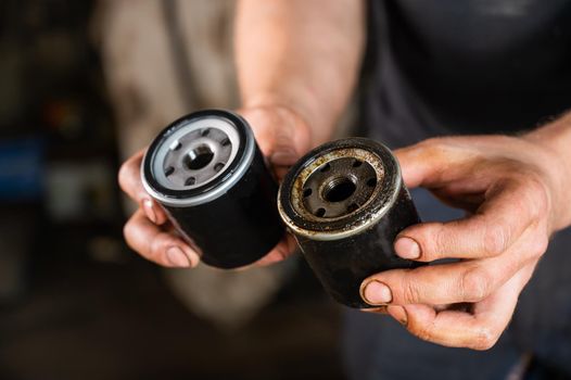 An auto mechanic holds a new and used oil filter.