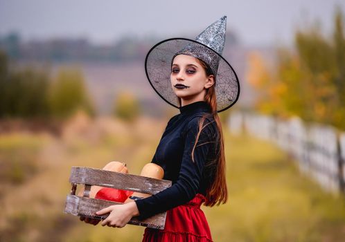 Gothic young girl holding pumpkins box