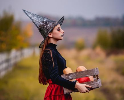 Gothic young girl holding pumpkins box