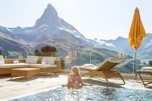 Woman enjoying the panoramic view from the pool in the alps