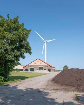 farm barn in wieringermeer near wind turbine under blue sky