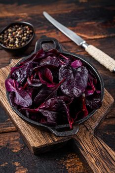 Swiss red chard or Mangold salad Leafs in a pan. Dark wooden background. Top view