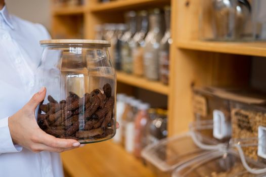A woman holds croutons in a glass jar. Eco shop without plastic waste.