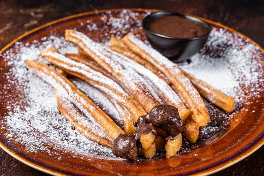 Spanish tapas churros with sugar and chocolate sauce. Dark background. Top view