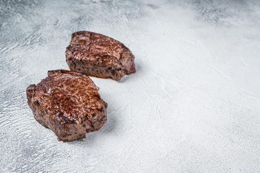 Grilled fillet mignon or tenderloin beef steak on kitchen table. White background. Top view. Copy space
