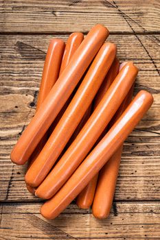 Raw frankfurter sausages on kitchen table. Wooden background. Top view