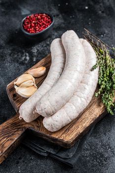 Raw Munich white sausage weisswurst on wooden board. Black background. Top view