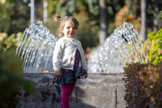 charming toddler in the park with fountains in the background