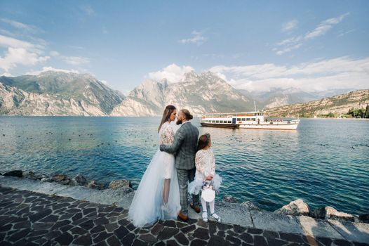 Italy, Lake Garda. Beautiful family on the shores of lake Garda in Italy at the foot of the Alps. Father, mother and daughter in Italy