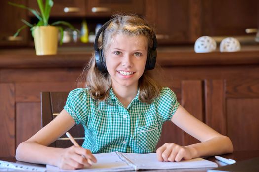 Head shot of a pre-teen girl wearing headphones looking at the webcam at home