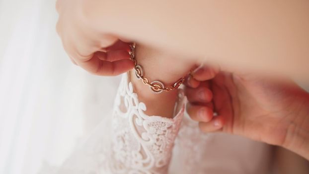 Bridesmaid puts bracelet on the bride's arm