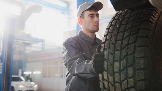 Car service - a mechanic checks the wheel of SUV, wide angle