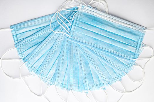 Several medical blue disposable protective masks one on top of other in form of fan on white background. surgical dressing closes mouth and nose. Healthcare, medicine, covid-19, epidemic concept.