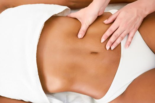 Woman receiving abdomen massage in spa wellness center.