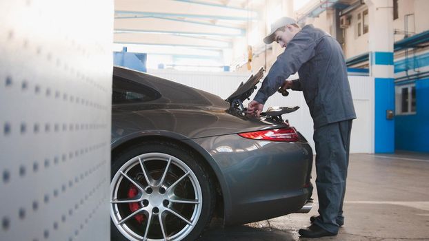 Mechanic in automobile garage checking hood for the luxury car
