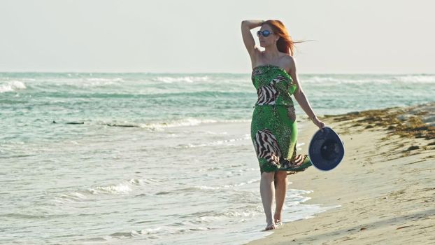 Young woman with long red hair walking at seascape beach in Dominican Republic