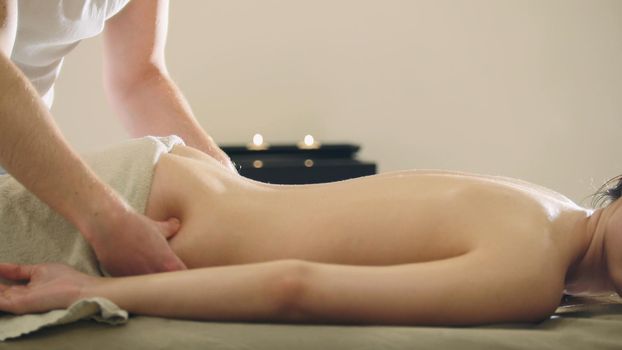 Young woman having classical massage in beauty spa, sesame oil