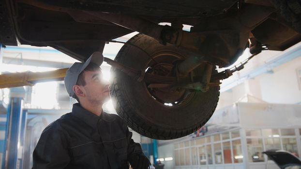 Garage automobile service - a mechanic checks the suspension, backlight