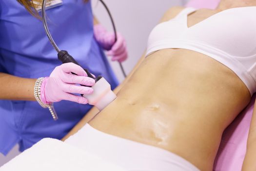 Woman receiving anti-cellulite treatment with radiofrequency machine in a beauty center.
