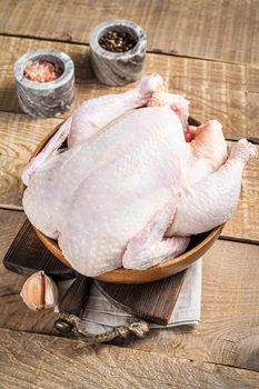 Organic chicken, raw poultry in a wooden plate. Wooden background. Top view