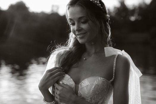 An elegant bride in a white dress enjoys nature at sunset.Model in a wedding dress in nature in the Park.Belarus. black and white photo