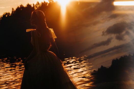 An elegant bride in a white dress enjoys nature at sunset.Model in a wedding dress in nature in the Park.Belarus
