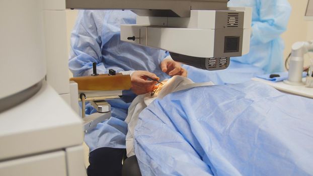 The patient lies on the operating surgical table during ophthalmology operation surgery wthout anesthesia - laser vision correction