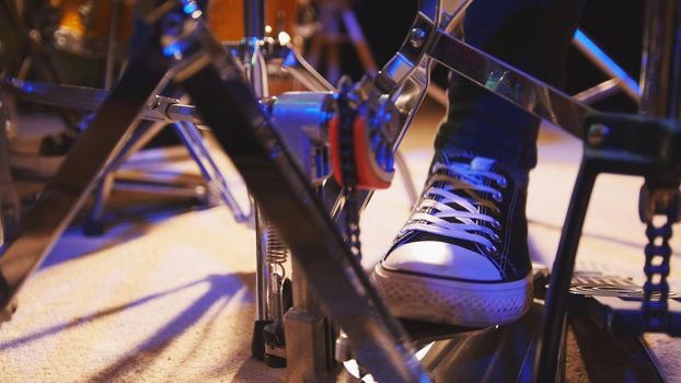 Drummer's foot in sneakers moving drum bass pedal