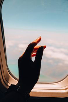 Female hand View from the window of the plane. Airplane, Aircraft. Traveling by air. Vacation travel concept Airplane Window View Above the Clouds Amazing golden fluffy clouds moving softly
