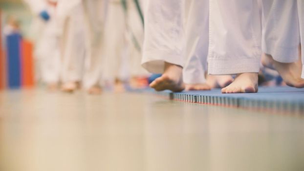 Karate training - teenagers in kimono runs on tatami in the gym