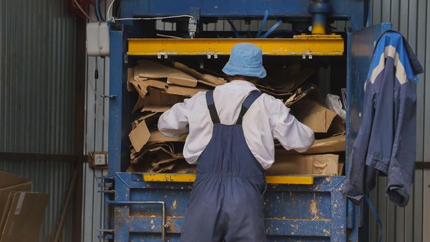 Worker on recycling of cardboard at industrial landfill, ecology concept