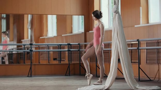 Young acrobatic girl shows the flexibility of the body at the ballet bar