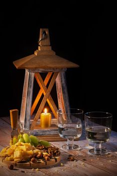 Cheese plate with a variety of snacks on the table with two glasses of wine by candlelight
