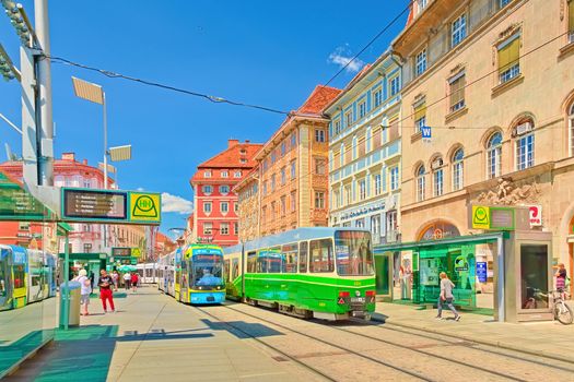 Graz - June 2020, Austria: View of a tram stop with colorful modern trams and beautiful old buildings in traditional architectural style