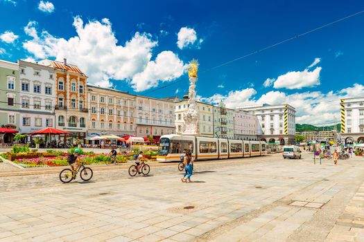 Linz - June 2020, Austria: View of the Main Square in Linz on a sunny summer day. A group of people riding bikes towards the city center