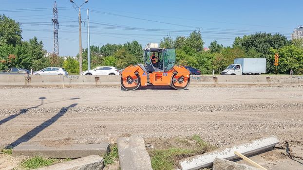 Ukraine, Kiev - October 1, 2019: Road roller, tractor and construction equipment are working on a new road construction site. The road is closed for road repair, route extension, pothole repair