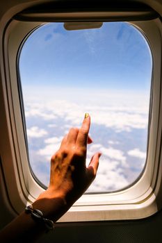 Female hand View from the window of the plane. Airplane, Aircraft. Traveling by air. Vacation travel concept Airplane Window View Above the Clouds Amazing golden fluffy clouds moving softly