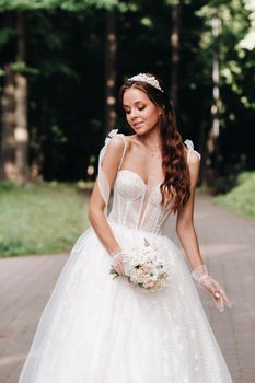portrait of an elegant bride in a white dress with a bouquet in nature in a nature Park.Model in a wedding dress and gloves and with a bouquet .Belarus