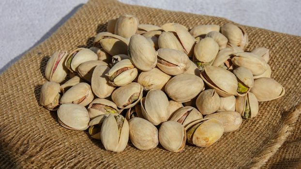 Pistachios in burlap sack on concrete table. Organic pistachios. Vegan Healthy food high protein. Dietary nutrition. Concept of nuts
