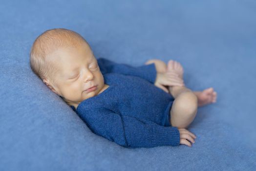sleepy newborn baby smiling and holding his leg