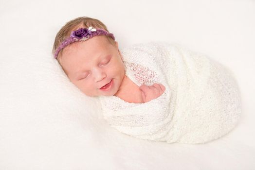 cute newborn in headband with flowers smiling asleep