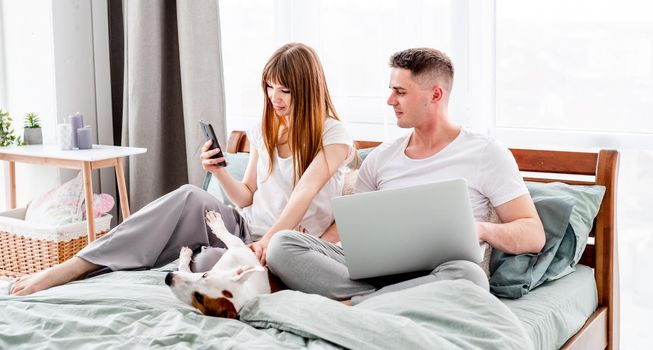 Couple in the bed with gadgets