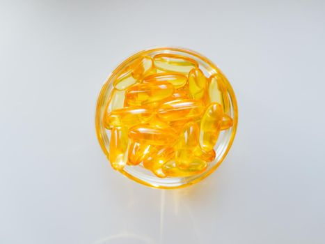 Fish oil capsules on a glass plate. A lot of vitamin omega 3 on a white background. Close-up, top view, high resolution product. Metabolism in the body. The body of calcium. A quick way to lose weight