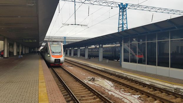 The high-speed passenger electric train Hyundai Rotem Tarpan HRCS2 Intercity stands on the platform of the central railway station in Kiev. Ukrainian railways. Ukraine, Kiev - June 09, 2021.