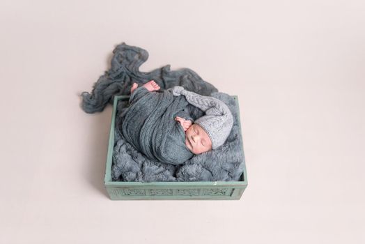 Newborn covered with dark blanket, topview