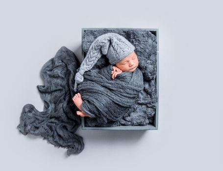 Newborn covered with dark blanket, topview