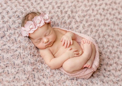 lovely newborn curled up asleep, wrapped in pink diaper