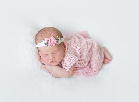 infant dressed in pink laced costume napping tightly